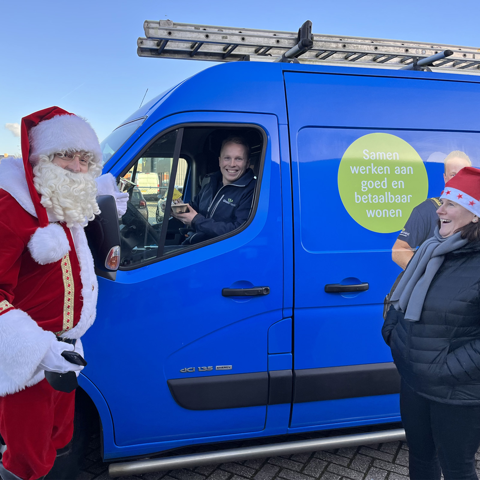 de kerstman in gesprek bij een WoonFrieslandbus met een monteur en een medewerker